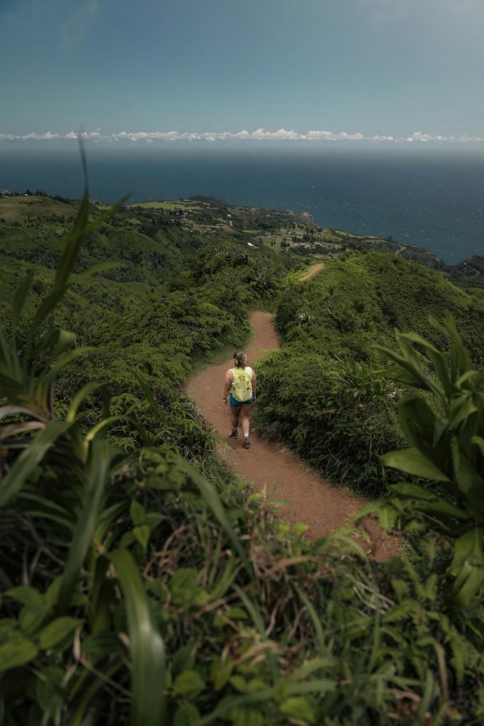 Woman hikes a trail with ocean views.